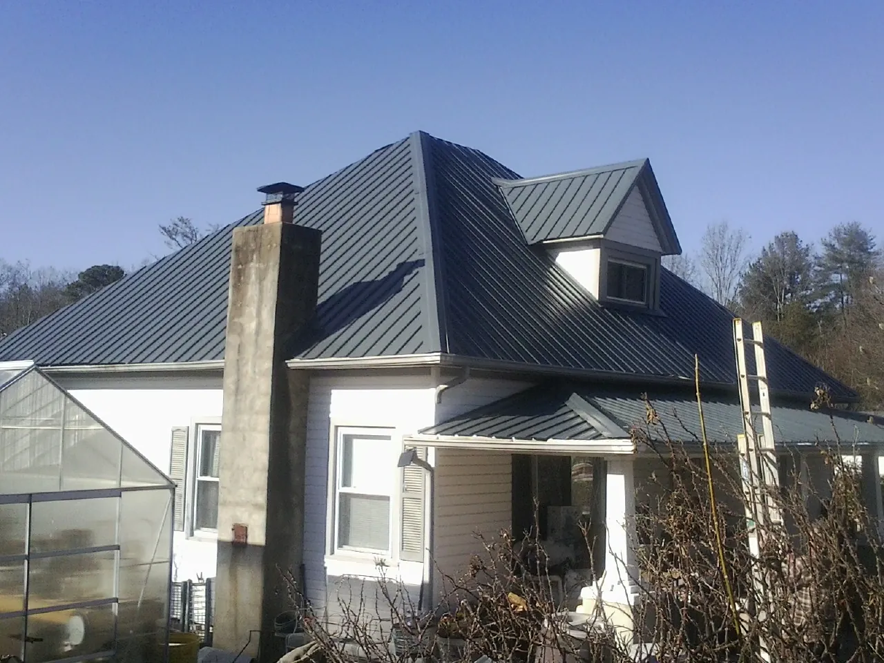 Dark blue standing seam metal roof on a white farmhouse with dormer — Slate & Tile Roof Repair by Roofing Brothers in Trabuco Canyon