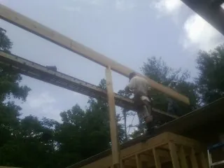 Carpenter setting a ridge beam over a new addition frame — Ice Dam Removal by Roofing Brothers in Trabuco Canyon
