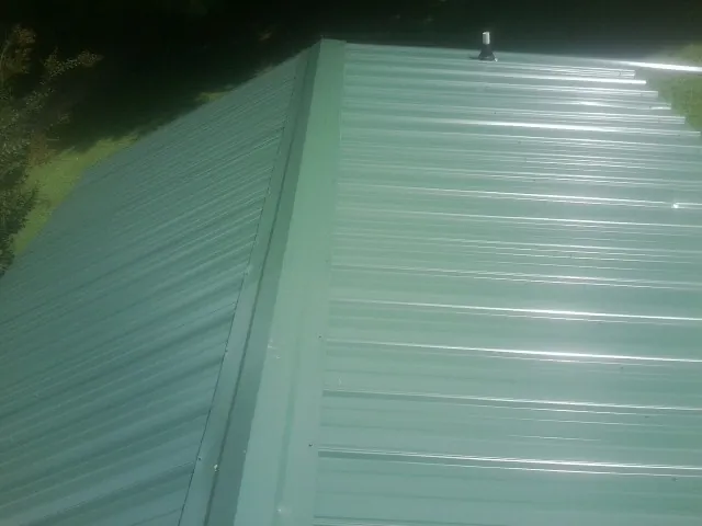 New green metal panels meeting at the ridge of a roof — Flat Roof Repair work by our crew in Trabuco Canyon