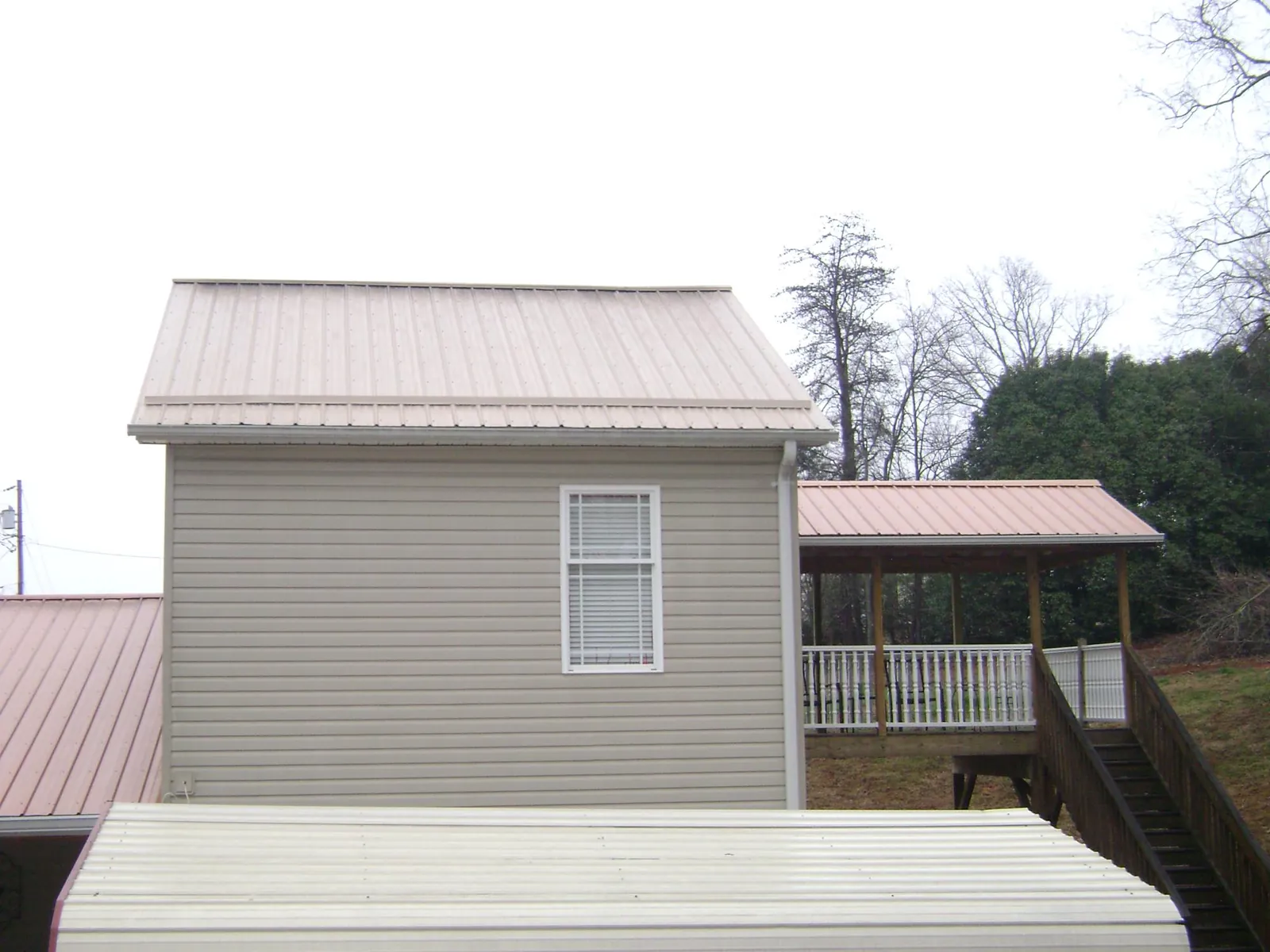 Tan metal roofs on a two story addition and attached porch, from a Roof Replacement job in Trabuco Canyon