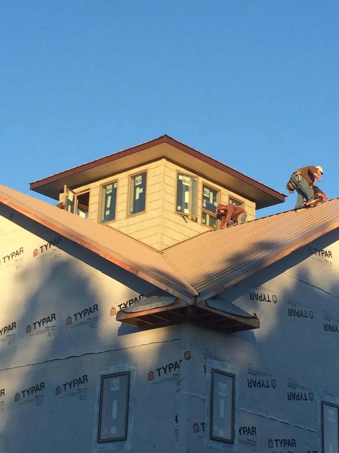 Roofers working around a rooftop cupola on a new metal roof at sunset — Roof Waterproofing in Trabuco Canyon by Roofing Brothers